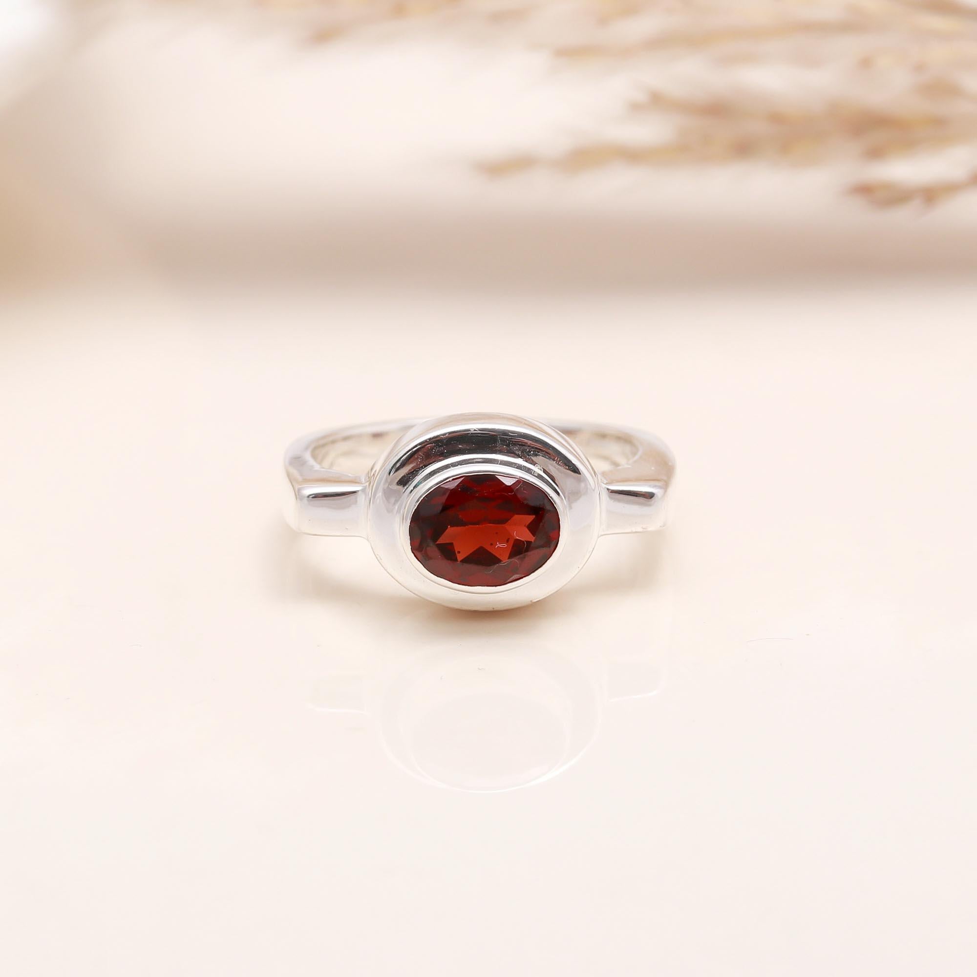 Close-up of oval garnet solitaire sterling silver ring