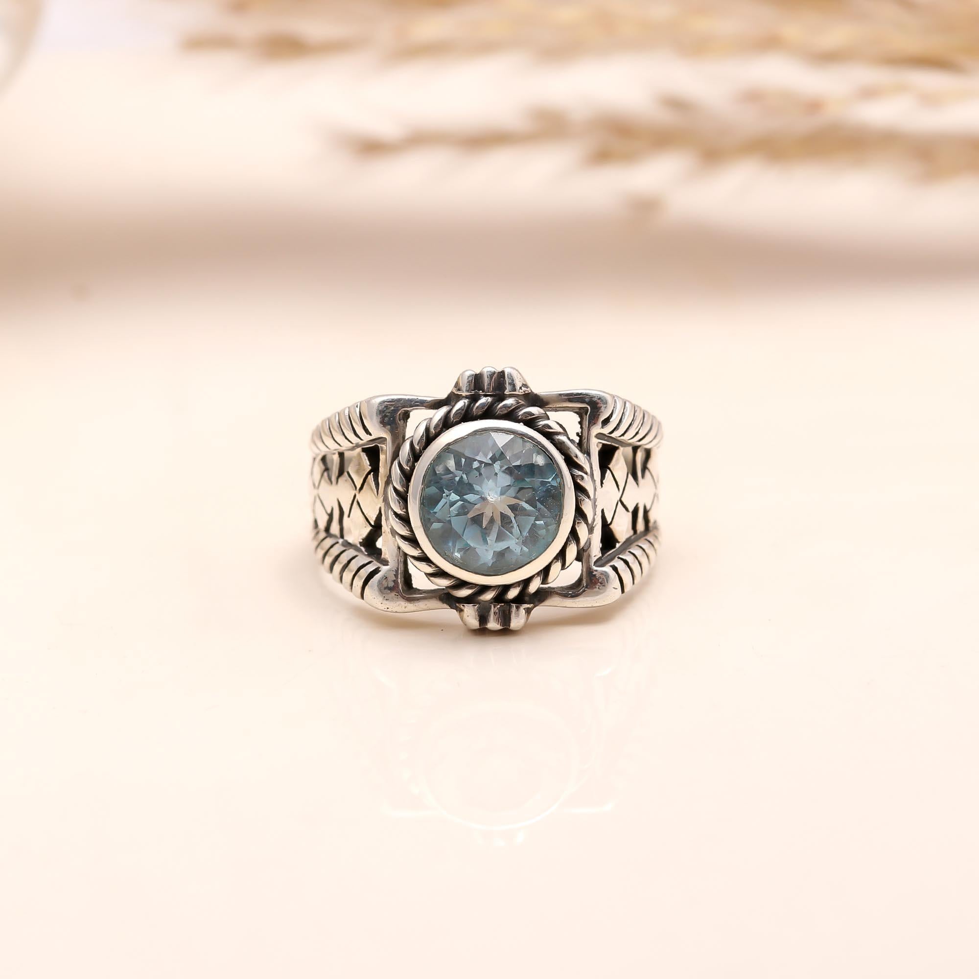 Close-up of round blue topaz with vintage patterned silver band