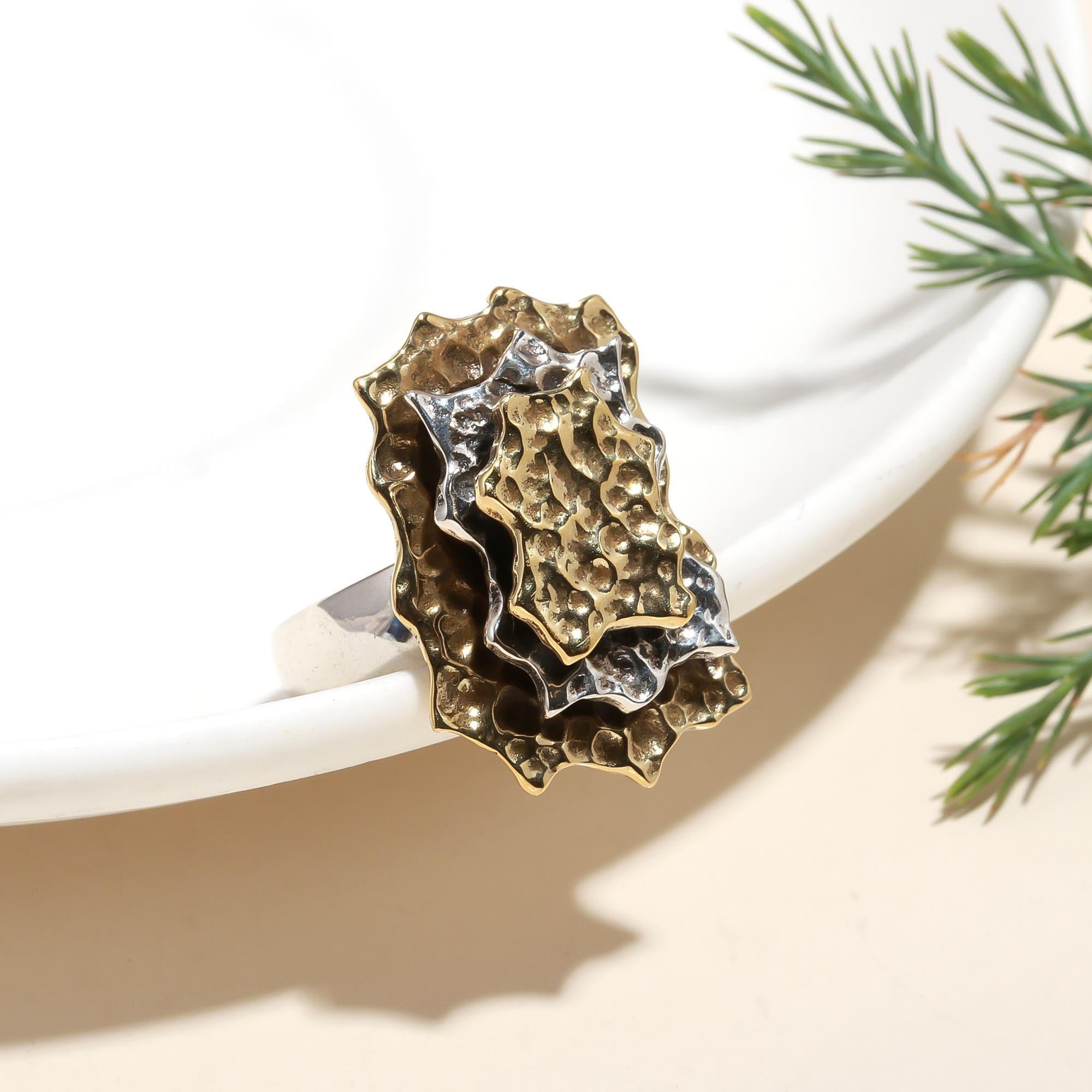 Gold and silver ring on a white surface with greenery