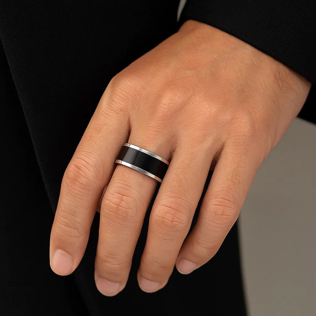 Hand wearing a black and silver ring on a neutral background
