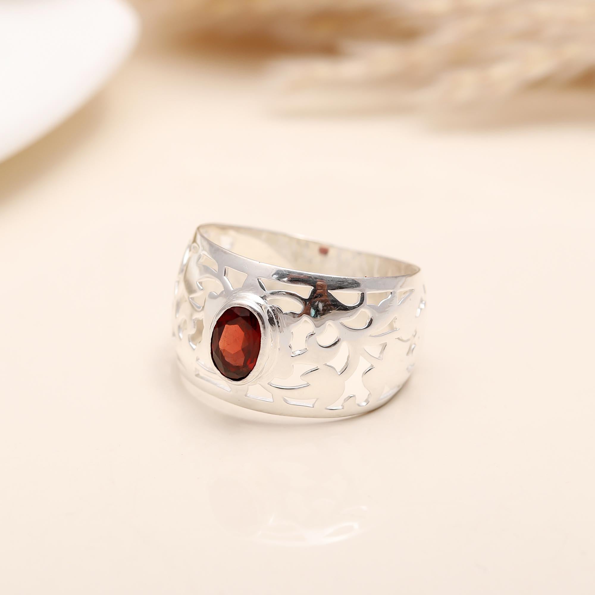 Detailed cutout filigree design on silver ring with garnet