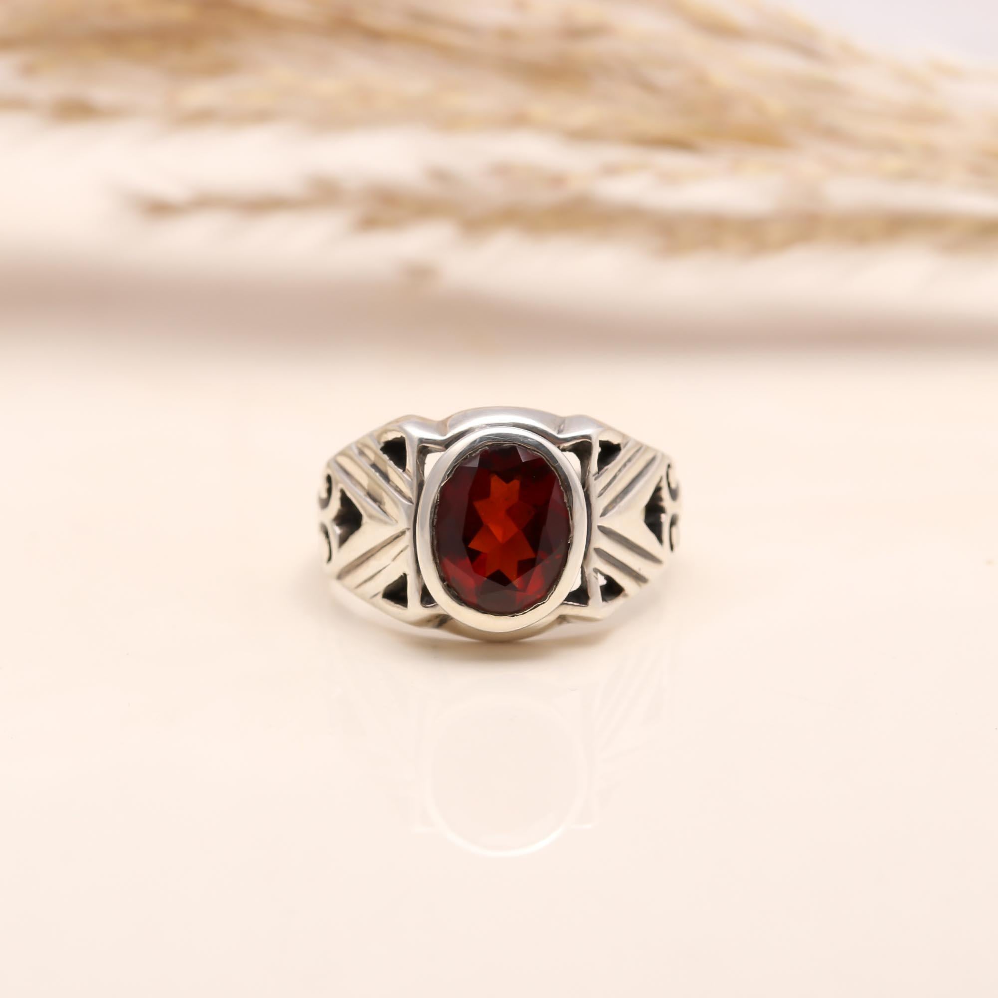 Close-up of oval garnet with vintage patterned silver band